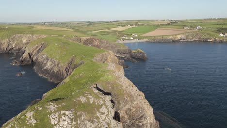 An-aerial-view-of-Abereiddi-Tower-in-Pembrokeshire,-South-Wales,-on-a-sunny-evening-with-a-clear-blue-sky