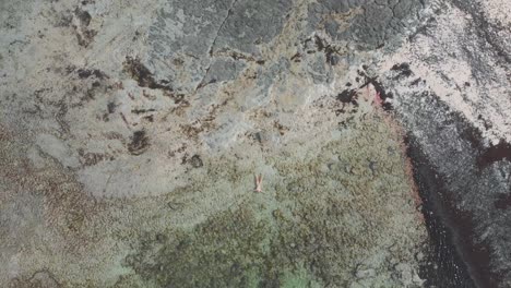 Serena-Escena-De-Una-Mujer-Flotando-Sola-En-Las-Tranquilas-Y-Transparentes-Aguas-De-Una-Hermosa-Playa-En-Fuerteventura,-Islas-Canarias.