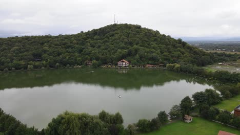 Aerial-view-of-lake-surrounded-by-mountains-green-trees-forest