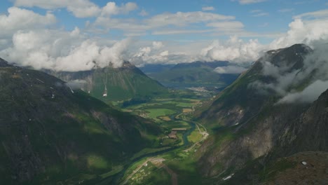 Aerial-view-of-Romsdalen-Valley,-Rauma-river-and-town-in-Norway-on-a-beautiful-sunny-day-with-clouds