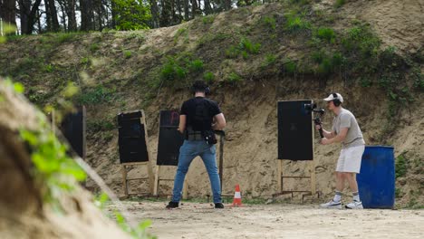 Detrás-De-Escena-En-El-Set-De-Filmación-Con-Un-Hombre-Armado-Y-Un-Camarógrafo,-Campo-De-Tiro-De-Olesko