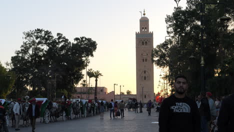 Carruaje-De-Caballos-Y-Gente-En-La-Calle-Cerca-De-La-Mezquita-Koutoubia-En-Marrakech,-Marruecos