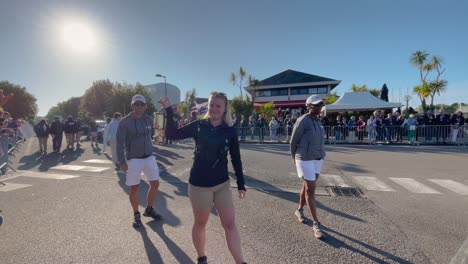 Blonde-woman-walking-showing-Paris-2024-Olympic-flame-to-the-street-crowd-surrounded-by-security-guards-on-a-sunny-day