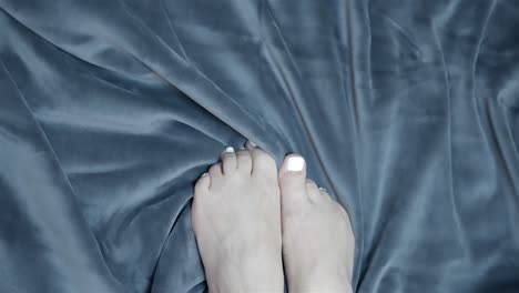 Top-down-pan-across-toes-as-they-grip-onto-smooth-soft-blanket