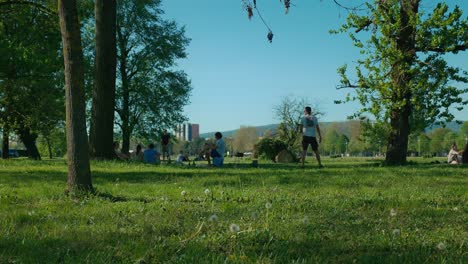 People-enjoying-various-activities-in-Jarun-Park,-Zagreb,-surrounded-by-trees-and-greenery-on-a-sunny-day