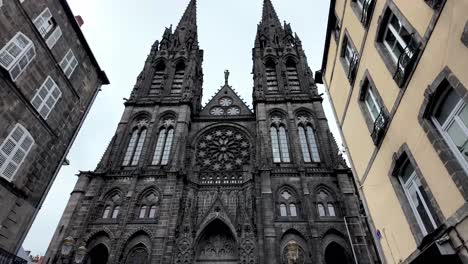 Architectural-beauty,-black-volcanic-rock-used-to-build-Notre-Dame-of-the-Assumption-in-Clermont-Ferrand,-a-street-view-with-pedestrians