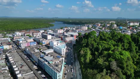 Vista-Aérea-De-La-Ciudad-De-Krabi,-En-El-Sur-De-Tailandia,-Que-Muestra-Una-Mezcla-De-Edificios,-Un-Río,-El-Mar-Y-Colinas-Boscosas-Al-Fondo.