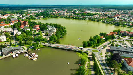 Aerial-view-of-Iława,-showcasing-the-town's-picturesque-lake,-urban-development,-and-green-spaces