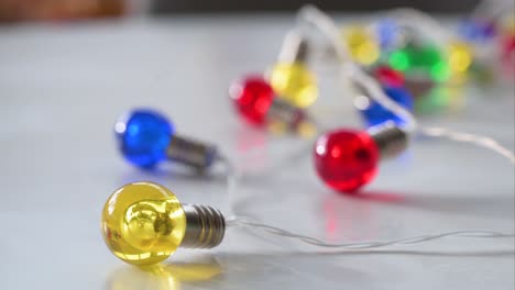 Christmas-LED-bulbs-in-festive-hues—blue,-red,-yellow,-and-green—adorn-a-white-surface