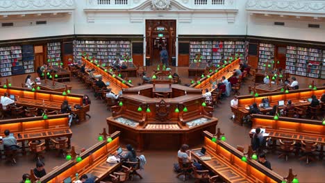 Gran-Interior-De-La-Sala-De-Lectura-La-Trobe-En-La-Biblioteca-Estatal-Victoria-En-La-Ciudad-De-Melbourne-Con-Hileras-De-Escritorios-De-Madera,-Lámparas-De-Lectura-Verdes-Y-Amplias-Estanterías,-Creando-Un-Ambiente-De-Estudio-Sereno