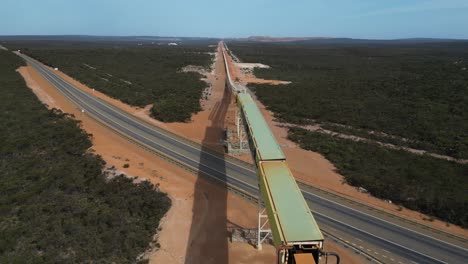 Vista-Aérea-De-La-Cinta-Transportadora-De-Mineral-De-Níquel-De-Una-Mina-Pasando-Por-Una-Carretera.