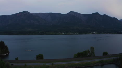 Blue-hour-dusk-glow-spreads-calmly-across-Columbia-River-Gorge,-aerial-establishing