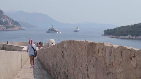 Impresionante-Vista-De-Mujeres-Caminando-Por-La-Muralla-De-La-Ciudad-De-Dubrovnik,-Croacia