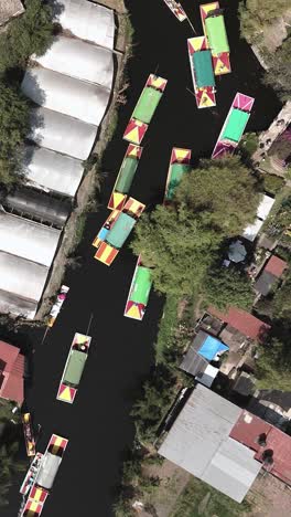 Trajineras-gliding-through-the-canals-of-Xochimilco,-vertical-mode