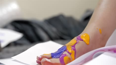 Sideview-of-foot-with-purple-paint-dropping-on-yellow-and-pink-top