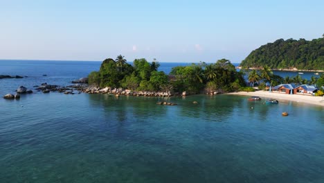 Lovely-aerial-view-flight-of-a-Hut-on-a-tropical-Sole-peninsula-with-turquoise-water-and-green-vegetation