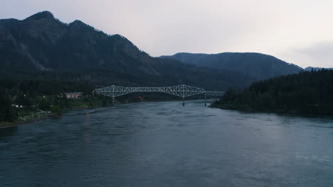 Soar-through-the-Columbia-River-Gorge-up-stream-in-PNW-to-white-cantilever-Bridge-of-the-Gods-at-blue-hour