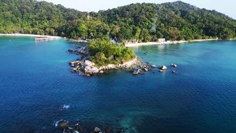 Breathtaking-aerial-view-flight-of-a-Hut-on-a-tropical-Sole-peninsula-with-turquoise-water-and-lush-green-vegetation