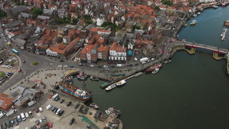 Puerto-De-Whitby-En-Inglaterra-Con-Barcos-Y-Edificios-Históricos,-Bullicioso-Día-De-Verano,-Vista-Aérea