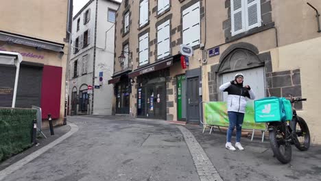 Walking-down-the-street-in-old-part-of-Clermont-Ferrand-on-weekend-with-only-delivery-and-restaurants-work,-with-typical-French-architecture