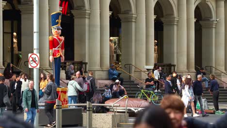 En-El-Bullicioso-Centro-De-Melbourne,-Un-Músico-Callejero-Toca-Música-En-Vivo-En-El-Centro-Comercial-Bourke-Street,-Atrayendo-Multitudes-Mientras-La-Gente-Pasea-Por-La-Calle,-Mostrando-La-Vibrante-Y-Próspera-Escena-Cultural-De-La-Ciudad.