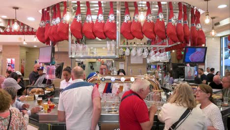 Customers-are-seen-at-a-Spanish-restaurant-bar-counter-in-Madrid,-Spain,-eating-and-ordering-numerous-tapas,-especially-Jamón-,-and-drinks