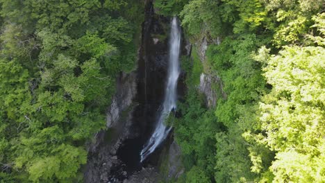 Aerial-view-of-waterfall-surrounded-by-green-planets-and-stones