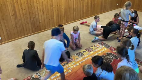 Children-solve-a-puzzle-together-under-the-teacher's-supervision-on-the-carpet