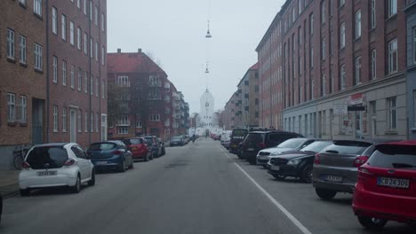 Street-in-Copenhagen-Denmark,-with-a-church-in-the-end-on-a-overcast-cold-winter-day