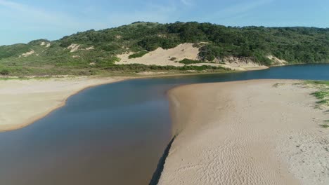 Aerial-view-of-a-coastal-lagoon-and-pristine-coastal-sand-dunes-and-forest,-South-Africa