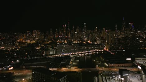 Aerial-view-over-the-river,-towards-high-rise-on-the-Near-north-side-of-Chicago,-nighttime-in-Illinois,-USA