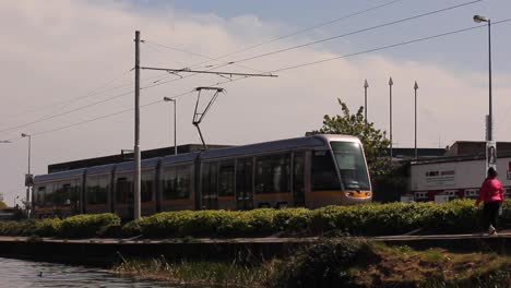 Dublin-public-transportation-luas-and-jogger-passes-by-the-canal-in-Dublin,-Ireland