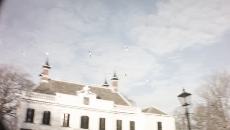 Velse-beek---Netherlands---January-22nd-2019:-spinning-circle-sky-look-view-of-Tanger-Advocaten-Ijmond-historical-buiding-in-winter-afternoon-during-sunset-with-seagull-birds-flying-in-Velse-beek