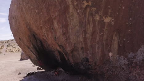 woman-tourist-siting-under-the-Largest-Granite-Boulder,-and-playing-with-her-dog-german-shepherd,-Yucca-Valley,-California-Desert