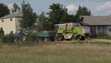 Ende-Des-Einfüllens-Von-Frisch-Gemähtem-Getreide-Aus-Dem-Mähdrescher-In-Einen-Anhänger,-Der-An-Den-Traktor-Gezogen-Wird