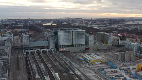 Aerial,-tracking,-drone-shot-panning-towards-the-Mall-of-Tripla-shopping-center-and-the-Pasila-railway-station,-on-a-cloudy-evening,-in-Helsinki,-Finland