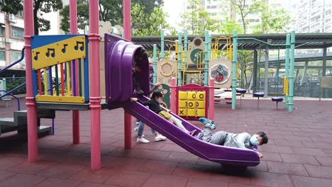 Pandemia-Del-Virus-De-La-Corona,-Niños-Jugando-En-Un-Patio-De-Recreo-En-El-Centro-De-Hong-Kong-Con-Máscaras-Protectoras-Para-La-Cara