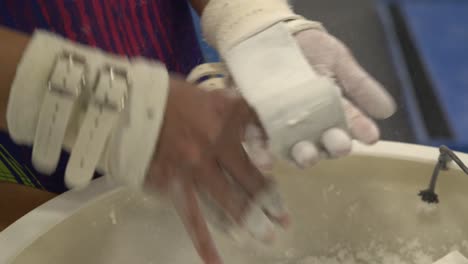 Asian-teen-gymnast-chalks-up-hands-before-performing-a-gymnastics-routine