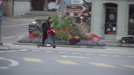 View-of-a-mother-and-daughter-passing-by-on-a-two-wheeler-standing-electric-scooter