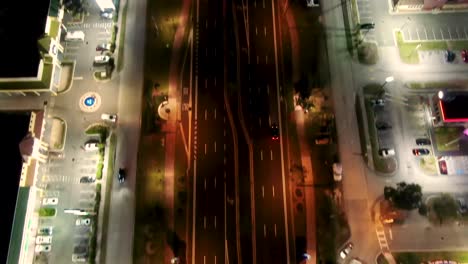 Ojo-De-Pájaro-Aéreo-Volando-Hacia-Adelante-Sobre-La-Avenida-Iluminada-Que-Revela-El-Horizonte-Nocturno