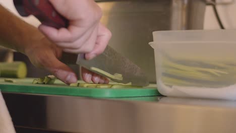 Hand-of-chef-finely-slices-zucchini