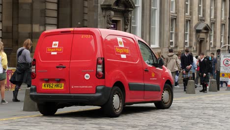 Small-red-van-Peugeot-Partner-of-the-Royal-Mail-postal-company-in-Edinburgh-with-people-like-tourists-going-around