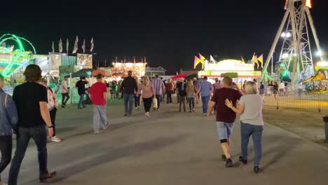 Eine-Aufnahme-Von-Glücklichen-Paaren,-Die-Händchen-Haltend-Eine-Straße-Entlanggehen-Und-Zum-Jährlichen-SBC-Jahrmarkt-Auf-Dem-Gelände-Des-Country-Fairs-Führen,-Einer-Jährlichen-Attraktion-Mit-Festlicher-Karnevalsatmosphäre-Und-Fahrgeschäften