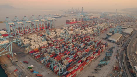 Algeciras-industrial-cargo-cranes-aerial-pull-back-above-stacked-containers-in-Cadiz-commercial-freight-harbour