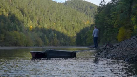 Young-man-is-standing-on-a-wooden-landing-stage-while-fishing-with-a-fishing-rod-at-the-local-reservoir