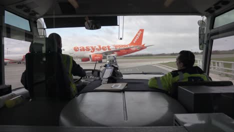 Static-shot-of-drivers-on-the-airport-from-the-shuttle-bus-when-the-easy-jet-airplane-passes-in-front-of-the-bus-in-reverse