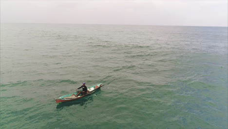 AERIAL:-Smiling-Honduran-fisherman-on-canoe-paddling-towards-the-coast