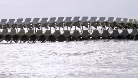 Handheld-side-pan-of-"Serpent-d'Océan"-sculpture-in-sea,-close-up