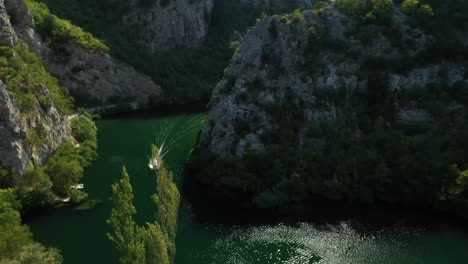 Imágenes-Aéreas-De-Drones-Siguiendo-Un-Barco-Rápido-En-Un-Cañón-Rocoso-Del-Hermoso-Río-Cetina-De-Color-Esmeralda-En-Croacia---Vídeo-De-Stock