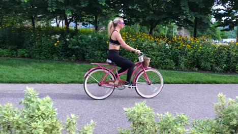 Tracking-a-fit-blonde-caucasian-girl-on-a-pink-bicycle-on-a-trail